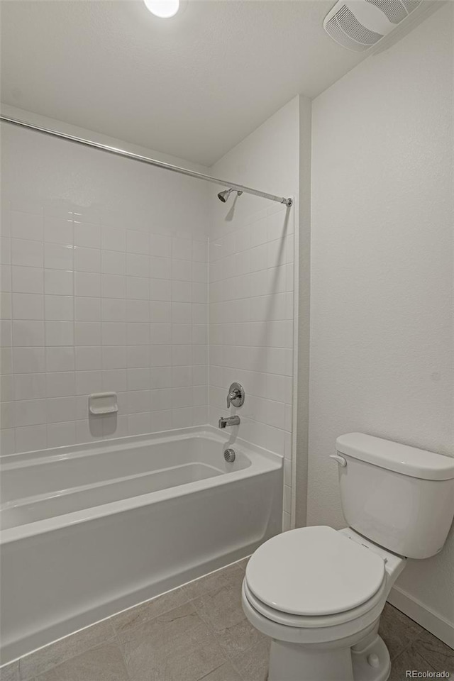 bathroom with toilet, tile patterned floors, and tiled shower / bath