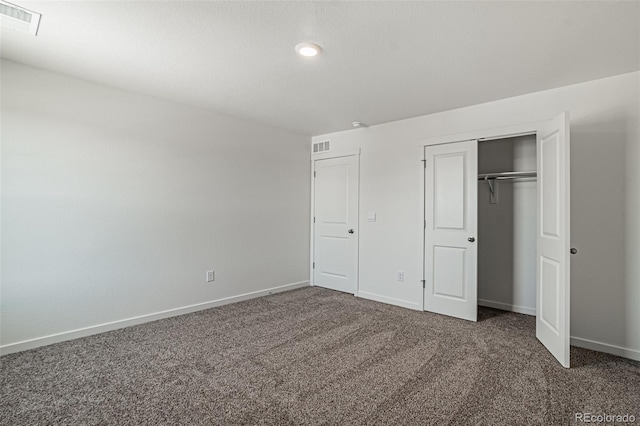 unfurnished bedroom with dark carpet and a closet