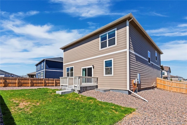 rear view of house featuring a wooden deck and a lawn