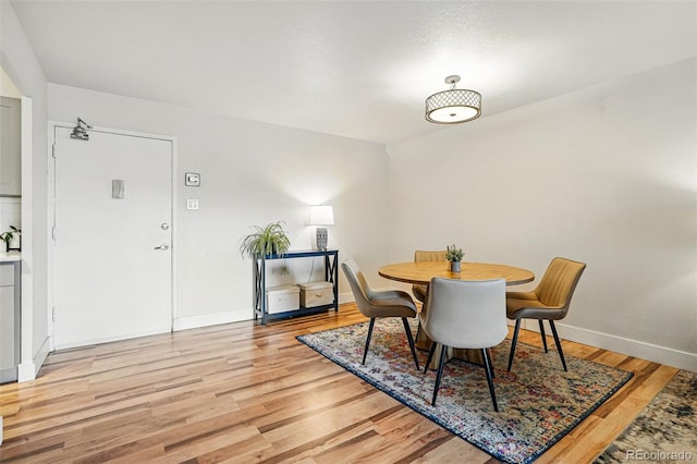 dining space featuring baseboards and light wood-style flooring
