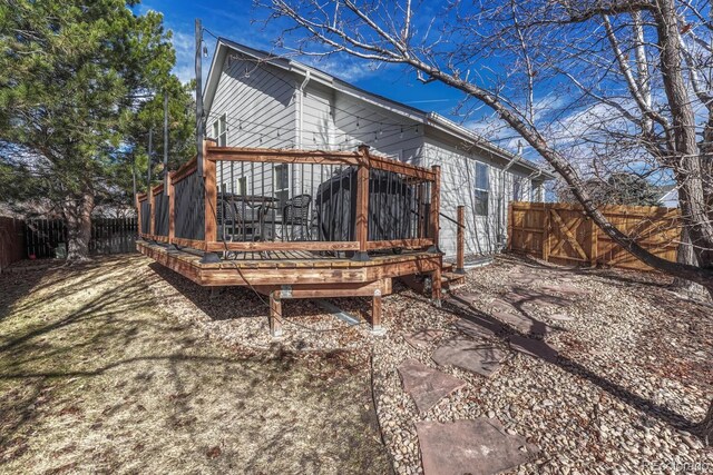 rear view of property featuring a fenced backyard and a wooden deck