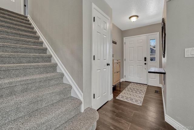 foyer with baseboards, stairway, and dark wood finished floors