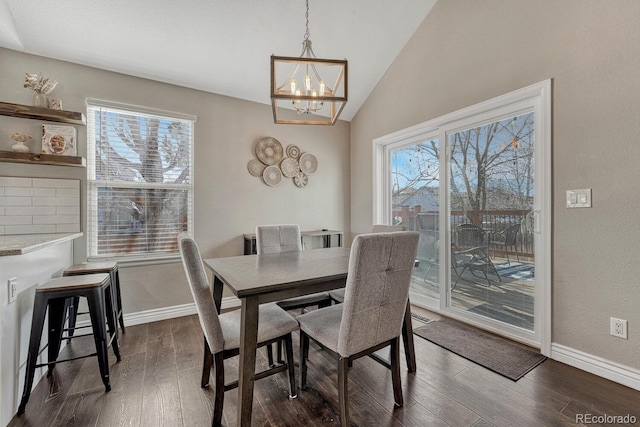 dining area featuring dark wood-style flooring, a notable chandelier, vaulted ceiling, and baseboards