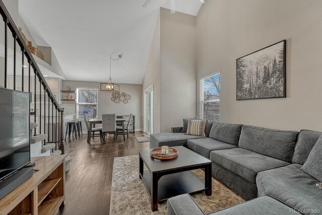 living area with stairway, wood finished floors, a towering ceiling, and baseboards