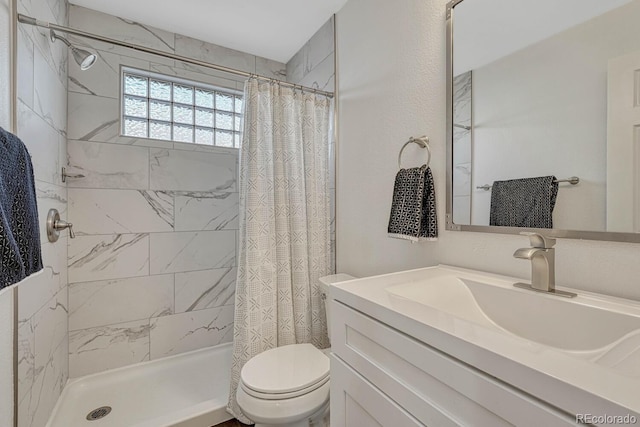 full bath with tiled shower, vanity, and toilet