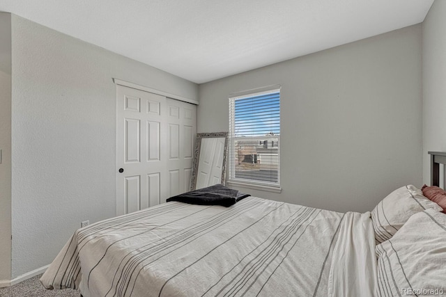 carpeted bedroom featuring a textured wall, a closet, and baseboards