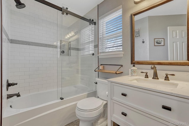 bathroom featuring combined bath / shower with glass door, a textured wall, vanity, and toilet