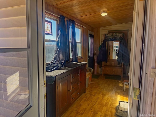 hall with radiator heating unit, wooden walls, light hardwood / wood-style floors, vaulted ceiling, and wooden ceiling