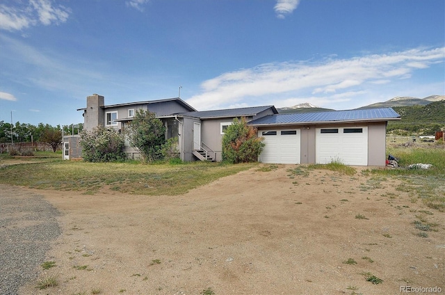 35805 US Highway 24, Buena Vista, CO 81211 - view of front of home with a metal roof, dirt driveway, a garage, and a chimney