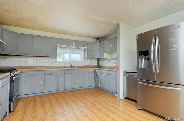 35805 US Highway 24, Buena Vista, CO 81211 - kitchen featuring stainless steel appliances, gray cabinetry, light wood-style floors, decorative backsplash, and a textured ceiling