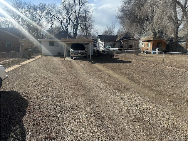 view of yard featuring driveway, a carport, and fence