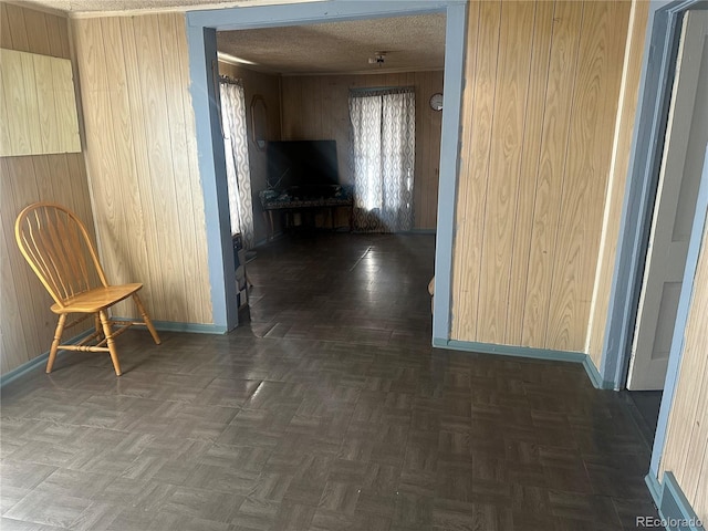 hallway with wooden walls, baseboards, and a textured ceiling