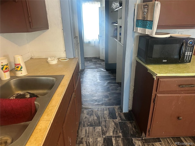 kitchen with brown cabinets, black microwave, light countertops, and a sink