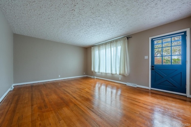 foyer entrance featuring wood finished floors, a textured ceiling, and baseboards