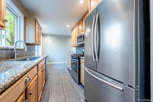 kitchen featuring appliances with stainless steel finishes, a sink, decorative backsplash, baseboards, and recessed lighting