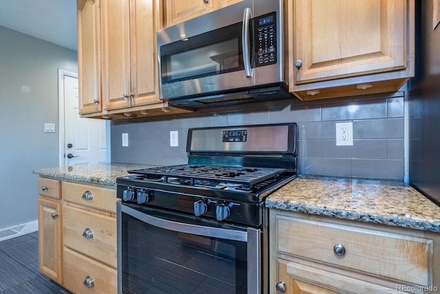kitchen with stainless steel appliances, backsplash, light brown cabinets, and light stone countertops