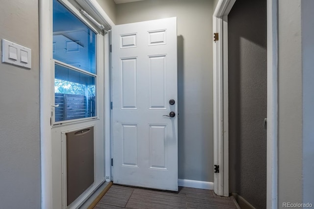 doorway to outside featuring baseboards and dark tile patterned floors