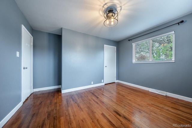 spare room featuring baseboards and wood finished floors
