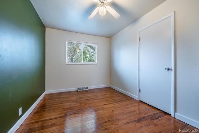 unfurnished room featuring wood finished floors, a ceiling fan, and baseboards