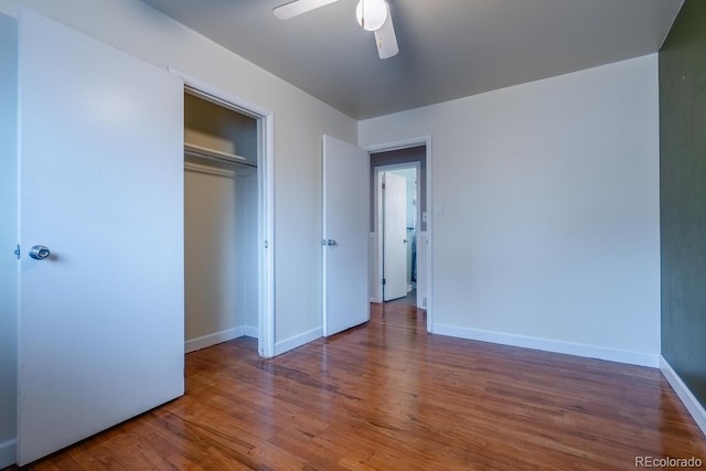 unfurnished bedroom with wood finished floors, baseboards, a closet, and a ceiling fan