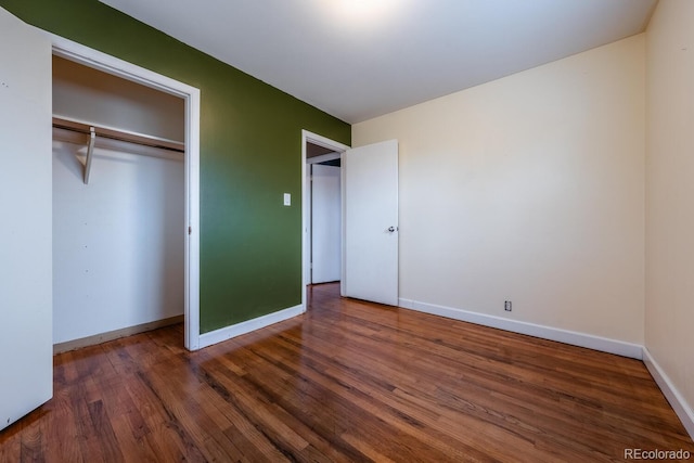 unfurnished bedroom with wood finished floors, baseboards, and a closet