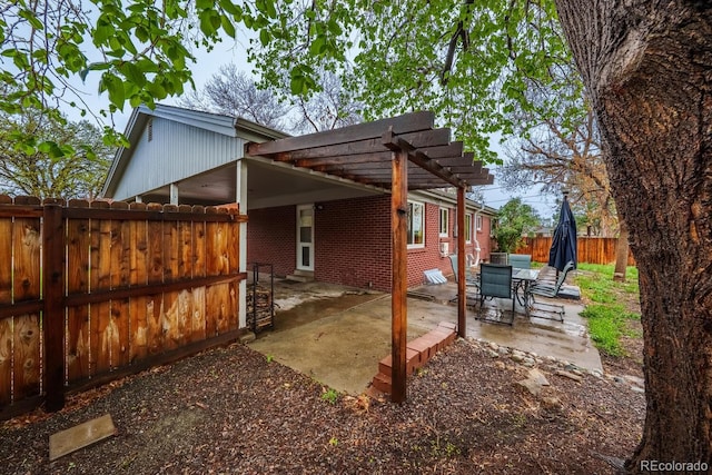 view of side of home with a fenced backyard, brick siding, a patio, and a pergola