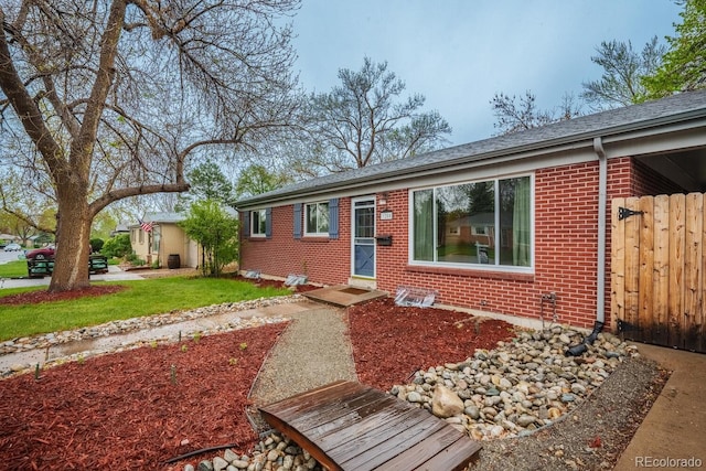 single story home featuring brick siding, entry steps, and roof with shingles