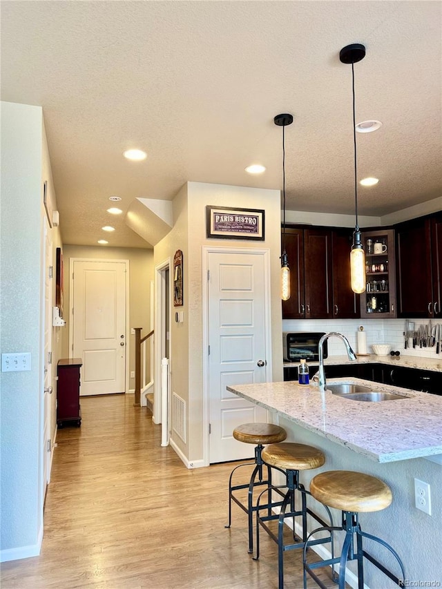 11235 S Neu Towne Cir, Parker, CO 80134 - kitchen featuring a sink, dark brown cabinets, a kitchen breakfast bar, recessed lighting, and light wood-style floors