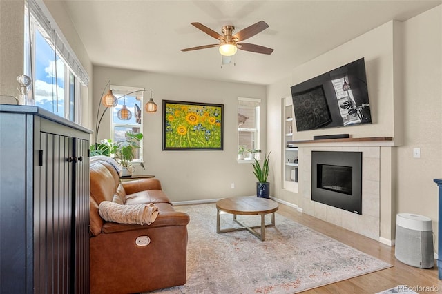 11235 S Neu Towne Cir, Parker, CO 80134 - living room featuring a ceiling fan, wood finished floors, a tiled fireplace, baseboards, and built in features