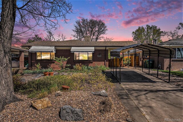 ranch-style house with a carport, a chimney, brick siding, and driveway