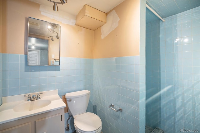 bathroom with tile walls, toilet, a tile shower, and vanity