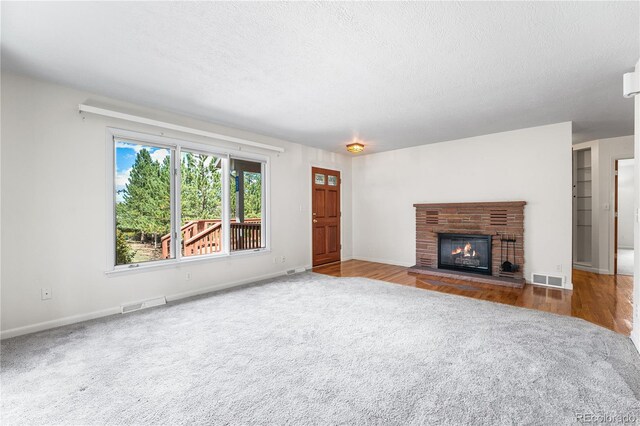 unfurnished living room featuring a textured ceiling, hardwood / wood-style floors, and a fireplace