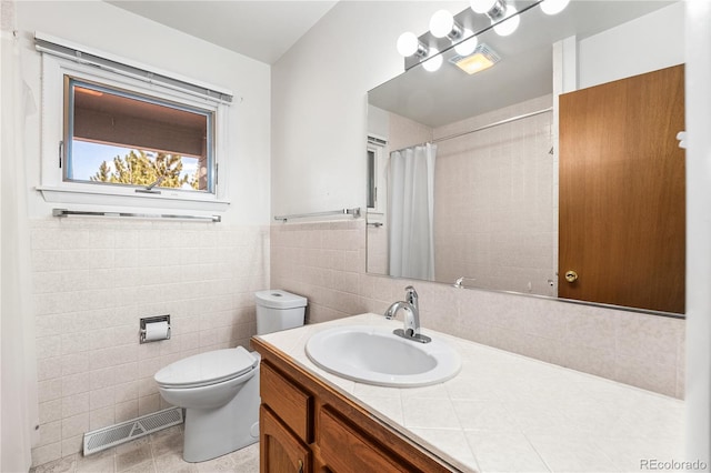 bathroom featuring a shower with shower curtain, tile patterned flooring, toilet, tile walls, and vanity