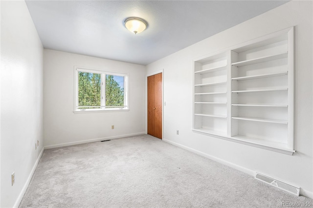 carpeted empty room with built in shelves