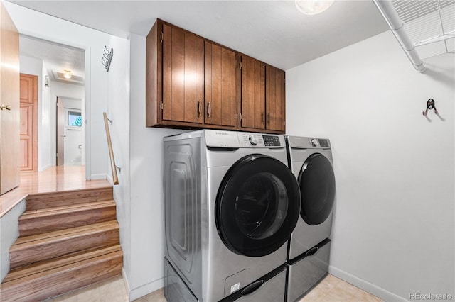 laundry room with light tile patterned floors, cabinets, and washer and dryer