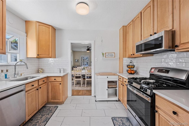 kitchen featuring ceiling fan, backsplash, appliances with stainless steel finishes, and sink