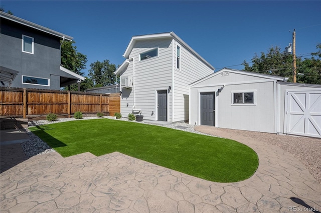 back of property with an outbuilding, a yard, and a patio