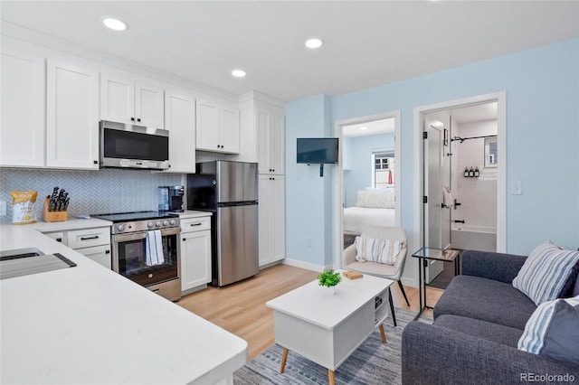 kitchen featuring tasteful backsplash, light hardwood / wood-style flooring, stainless steel appliances, and white cabinetry