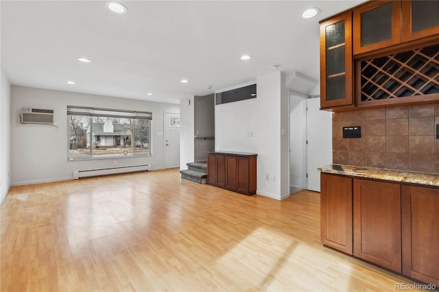 interior space with a baseboard heating unit, a wall mounted air conditioner, and light wood-type flooring