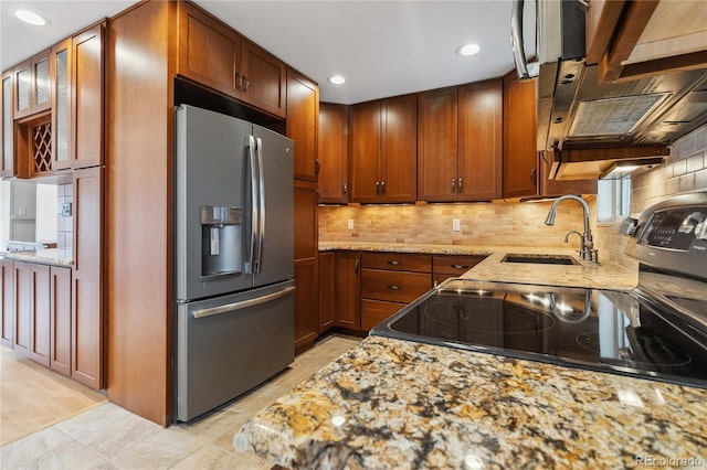 kitchen featuring light stone counters, sink, decorative backsplash, and stainless steel appliances