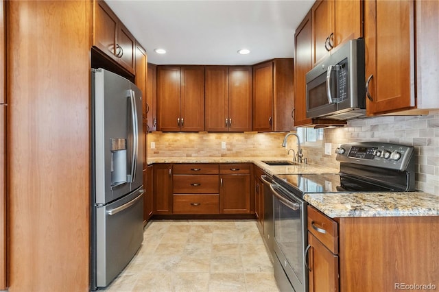 kitchen featuring sink, backsplash, stainless steel appliances, and light stone countertops