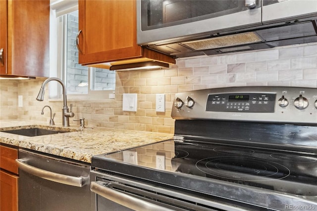 kitchen featuring sink, backsplash, stainless steel appliances, and light stone countertops