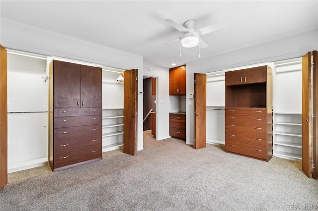 unfurnished bedroom with multiple closets, light colored carpet, and ceiling fan