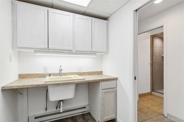 interior space with tile patterned flooring, a baseboard heating unit, and sink