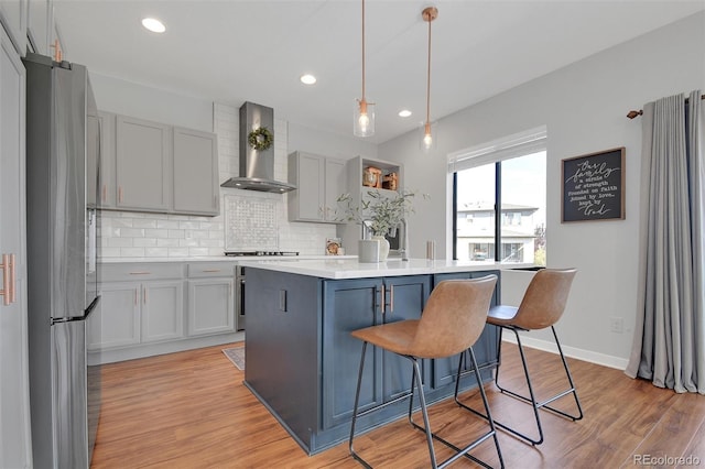 18085 E 107th Pl, Commerce City, CO 80022 - kitchen with freestanding refrigerator, wall chimney exhaust hood, gray cabinets, tasteful backsplash, and a breakfast bar area