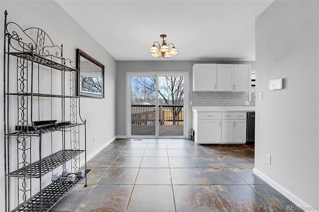 interior space with an inviting chandelier, backsplash, and white cabinets