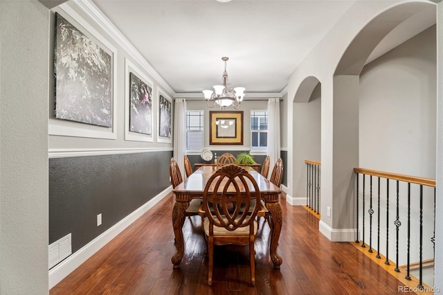 dining area with ornamental molding, wood-type flooring, and a notable chandelier