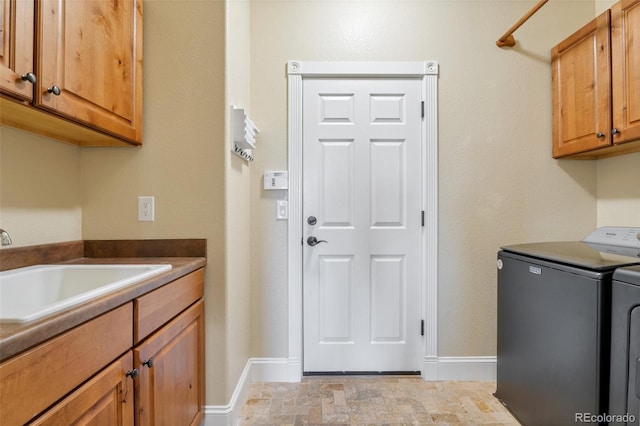 laundry area featuring cabinets, separate washer and dryer, and sink