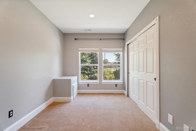 unfurnished bedroom featuring light colored carpet and a closet