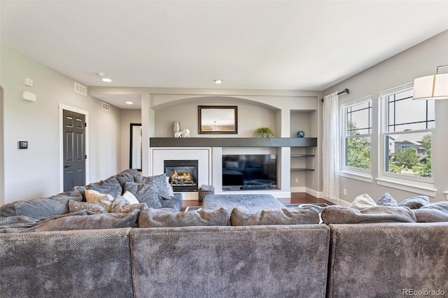 living room featuring built in shelves and hardwood / wood-style flooring